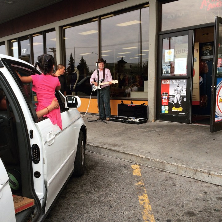 A child listens to a performance by street musician Hollis Rounder outside Red Apple in July.